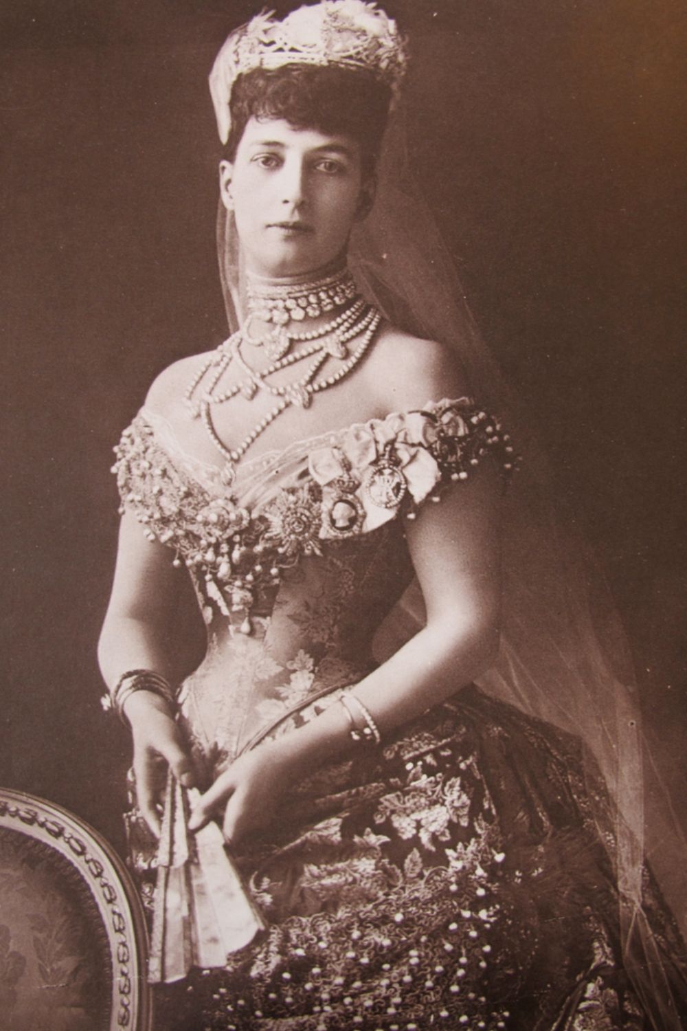 An Edwardian-era royal figure adorned with lavish pearl chokers
