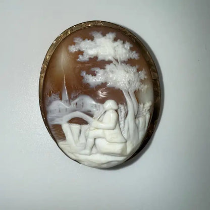 Victorian Shell Cameo Brooch Featuring Seated Flutist, Tree, and Bridge in Pastoral Scene, Late 19th Century